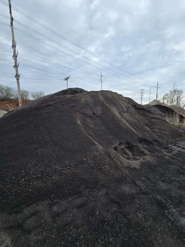 20260416_105405 - wnyDIRT.com Large mound of black coal piled outdoors with power poles and lines in the background on a cloudy day.